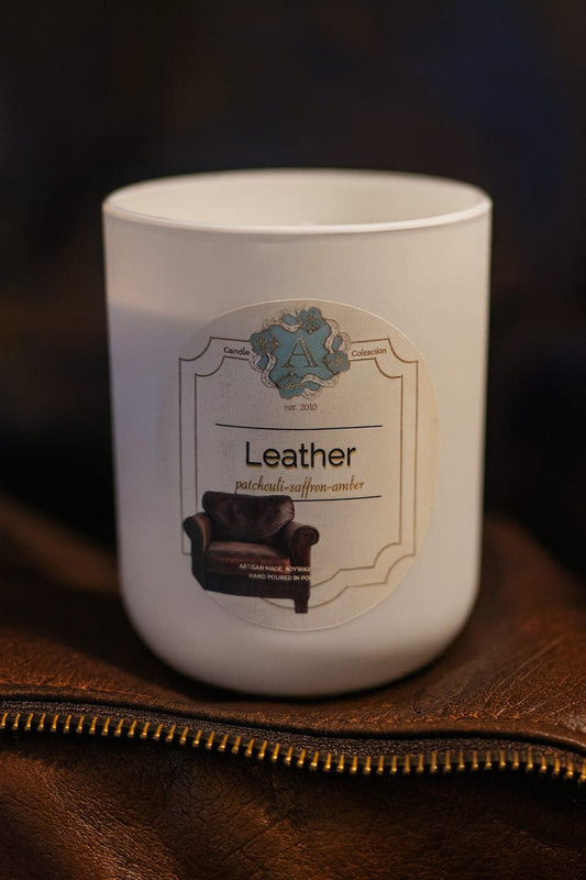 leather soy wax scented candle in a white jar on a brown leather surface – A Candle Collection